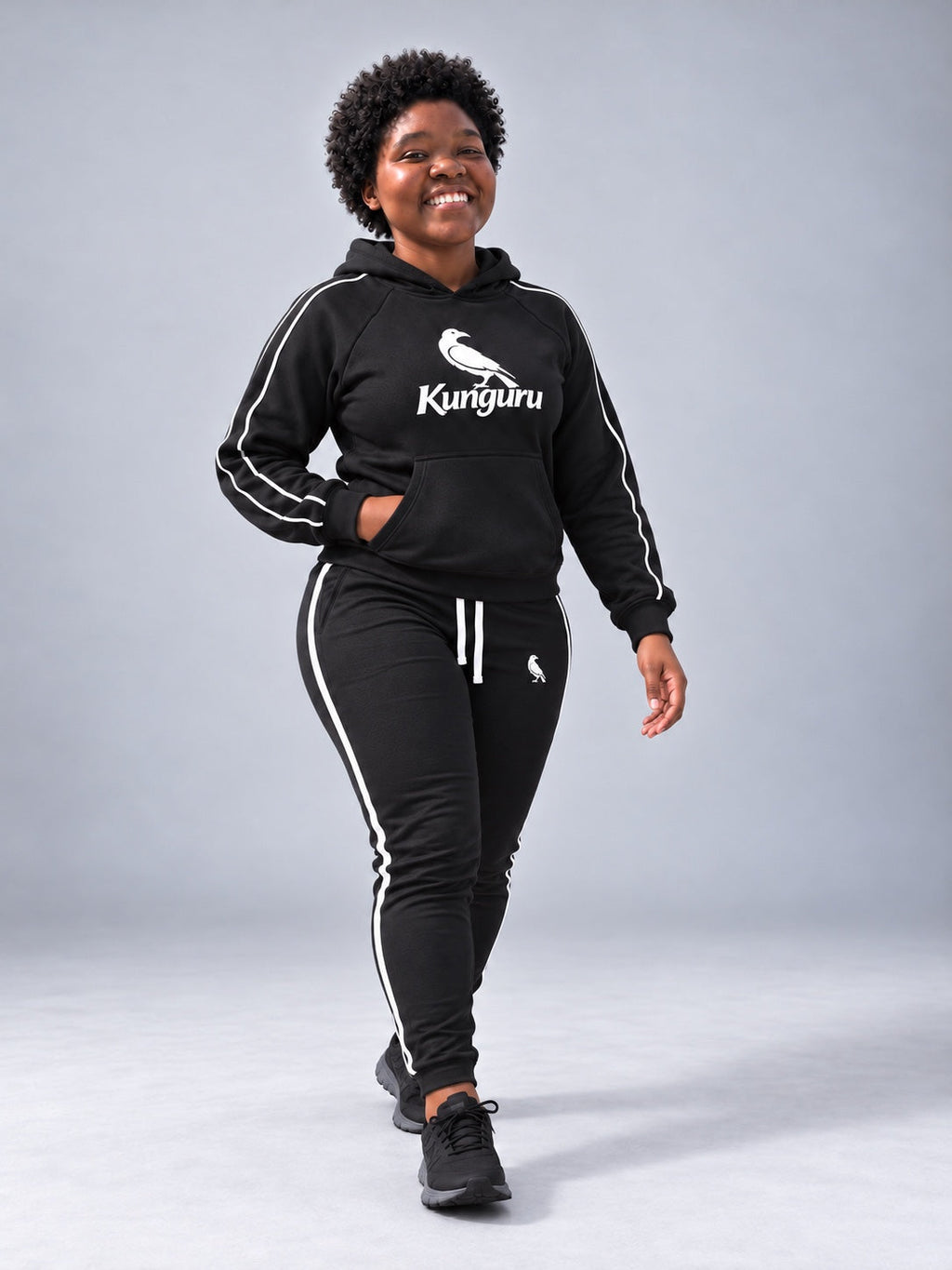 Woman wearing black Kunguru Hoodie and MBK Women Track Pant — studio pose 1