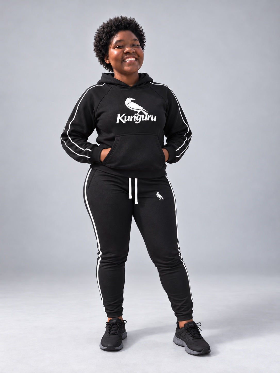 Woman wearing black Kunguru Hoodie and MBK Women Track Pant — studio pose 2