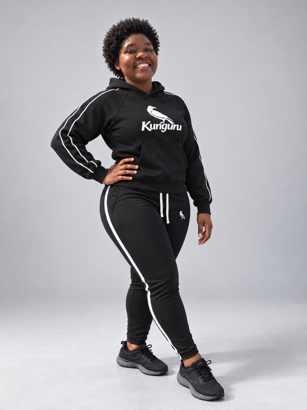 Woman wearing black Kunguru Hoodie and MBK Women Track Pant — studio pose 3